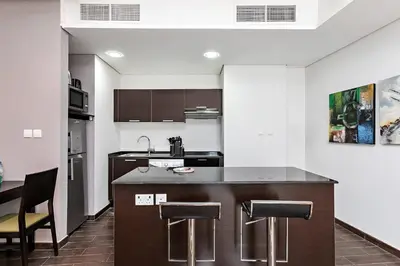 a kitchen with a counter and some chairs in it at Comfy 1BR apartment in Sport City in Dubai