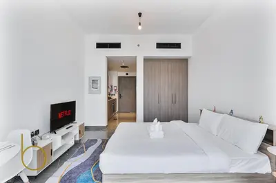 a bedroom with a large white bed and a tv at Bookable Studio Room Joya Blanca,Arjan with Tennis court access in Dubai