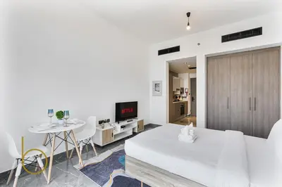 a white living room with a white couch and a table at Bookable Studio Room Joya Blanca,Arjan with Tennis court access in Dubai