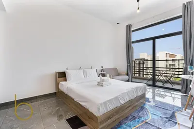 a bedroom with a bed and a large window at Bookable Studio Room Joya Blanca,Arjan with Tennis court access in Dubai