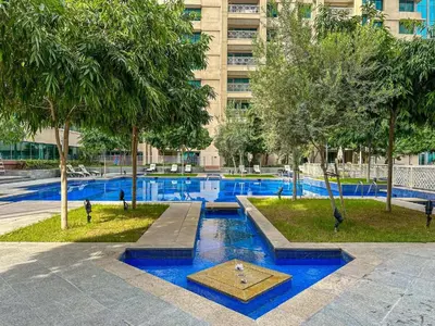 a swimming pool with blue water and trees and a building at Chic Downtown Studio Few Steps to Burj Khalifa by Simply Comfort in Dubai