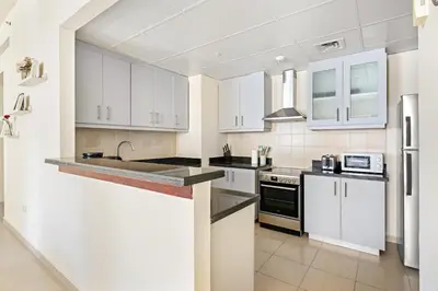 a white kitchen with white cabinets and a sink at VayK - Beautiful 1BR in JBR near the Beach in Dubai