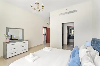 a living room with a blue couch and a mirror at VayK - Beautiful 1BR in JBR near the Beach in Dubai