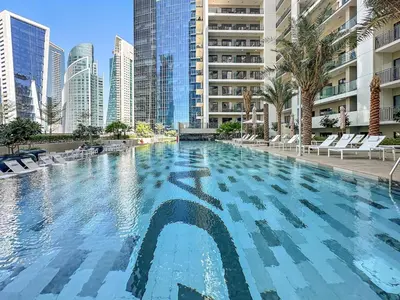 a large swimming pool in a city with tall buildings at FIRST CLASS 1BR Pool View & Prime Location in Dubai