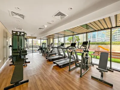 a gym with a bunch of treadms and cardio machines at FIRST CLASS 1BR Pool View & Prime Location in Dubai