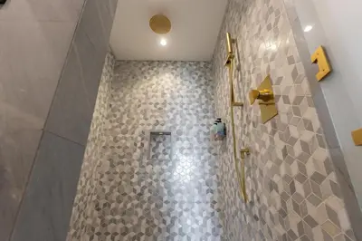 a bathroom with a shower with gray tiles at Five Palm Luxury Stay 2BR with Pool & Beach Access in Dubai