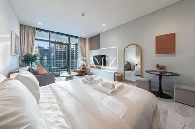 a bedroom with a large white bed and a living room at Modern Studio - Unit 1705 - Near Downtown in Dubai