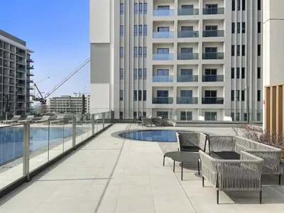 a patio with chairs and a swimming pool on a building at VayK - Brand New 1BR in Dubai Hills in Dubai