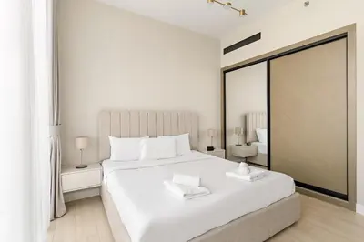 a white bedroom with a large bed with white pillows at VayK - Luxurious 2BR in JVC in Dubai