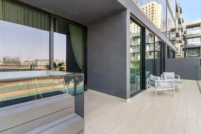 a balcony of a building with a pool and chairs at VayK - Luxurious 2BR in JVC in Dubai