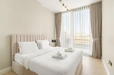 a white bedroom with a large bed with towels on it at VayK - Luxurious 2BR in JVC in Dubai