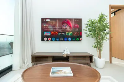 a living room with a table and a tv on the wall at PVH - Serene 1BR with City View - Binghatti House in Dubai