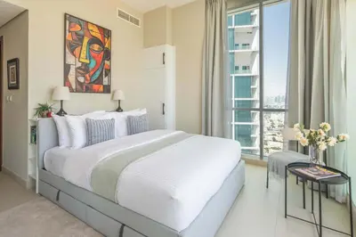 a white bedroom with a large bed and a window at Frank Porter - Hilliana Tower in Dubai