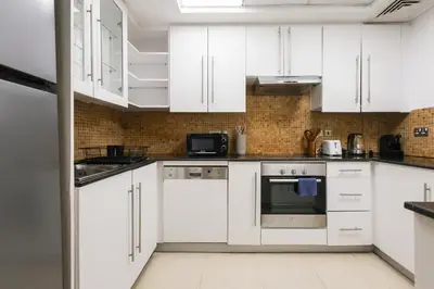 a white kitchen with white cabinets and appliances at Bright 2BR with Burj, Sea & City Views - Walk to Mall in Dubai