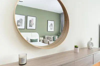 a living room with a round mirror on a dresser at HAVN - Studio in Alka, The Greens in Dubai