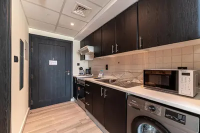 a kitchen with black cabinets and a washer and sink at HAVN - Studio in Alka, The Greens in Dubai