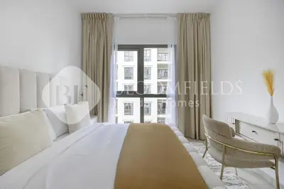 a white bedroom with a large bed and a desk at Bloomfields Cozy 1br Apt Town Square in Dubai