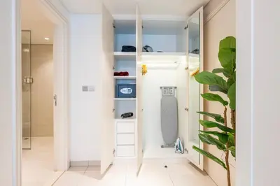 a walk in closet with white cabinets and a glass door at Chic 1 Bedroom in Business Bay in Dubai