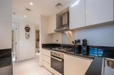 a kitchen with white cabinets and a stove top oven at Chic 1 Bedroom in Business Bay in Dubai