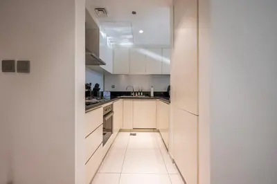 a kitchen with white cabinets and a white floor at Chic 1 Bedroom in Business Bay in Dubai