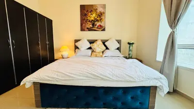 a bedroom with a large bed with a blue headboard at Beautiful 1 Bedroom Apartment close to metro in Dubai