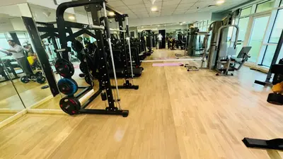 a gym with a row of tread machines on a wooden floor at Beautiful 1 Bedroom Apartment close to metro in Dubai