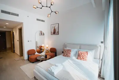 a bedroom with a bed and a chair at Azizi Riviera Modern Studio Near Downtown in Dubai