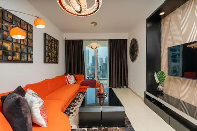an orange couch in a living room with a window at Comfortable - Vibrant - Convenient in Dubai