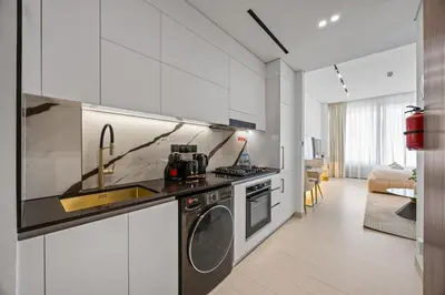 a kitchen with white cabinets and a washer and dryer at Luxury Studio with Private Jacuzzi &Canal View in Dubai