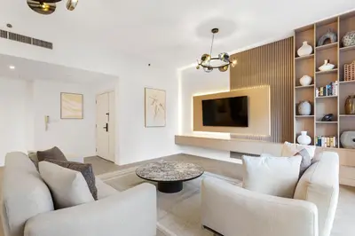 a living room with two chairs and a tv at Cozy 3 Bedroom with walking access to JBR Beach in Dubai