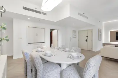 a white dining room with a white table and chairs at Cozy 3 Bedroom with walking access to JBR Beach in Dubai