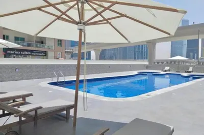 a pool with an umbrella and two chairs and a table at Locations l Upgraded 1 Bedroom l Marina Views l Free Pool Access in Dubai