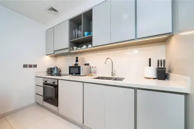 a white kitchen with white cabinets and a sink at Elegant 2 Bed Beach Front Retreat in Dubai