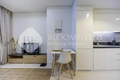 a kitchen with white cabinets and a table and chairs at Bloomfields Magnificent STU Aykon City in Dubai
