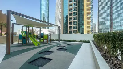 a playground with a slide in a city with tall buildings at Waterfront 1BR, Full Marina View & Pool Access - 34AB04 in Dubai