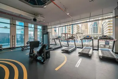 a gym with treadmills and a view of the city at Stylish 2BR Stay Near Marina Beach and Ain Dubai, Steps from Shops and Restaurants, Studio One, Dubai Marina by Deluxe Holiday Homes in Dubai
