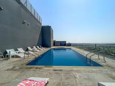 a swimming pool on top of a building with chairs at 2 Bed With Balcony Near World Renowned Golf Clubs in Dubai