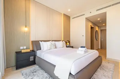 a bedroom with a large white bed and a night stand at Liv Marina Panoramic 3BR with Palm & Sea View in Dubai