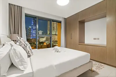a bedroom with a large white bed and a window at FIRST CLASS 2BR Burj Khalifa & Pool Views in Dubai