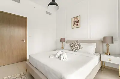 a white bedroom with a large bed with white sheets at FIRST CLASS 2BR Burj Khalifa & Pool Views in Dubai