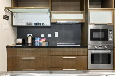 a kitchen with wooden cabinets and stainless steel appliances at Stunning 2BR in Downtown Partial Burj Khalifa View in Dubai