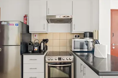 a kitchen with white cabinets and a stainless steel refrigerator at FIRST CLASS 2BR Vibrant Retreat Near JBR Beach in Dubai