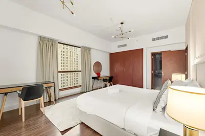 a bedroom with a white bed and a desk at FIRST CLASS 2BR Vibrant Retreat Near JBR Beach in Dubai