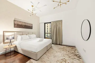 a white bedroom with a large bed and a mirror at FIRST CLASS 2BR Vibrant Retreat Near JBR Beach in Dubai