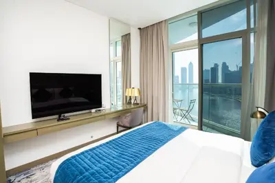 a bedroom with a large bed and a flat screen tv at Luxury Canal View Studio with Pool Damac Maison Prive in Dubai