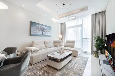 a white living room with a couch and a table at Maison Distinction Suites by Hostiva - Burj and Fountain View in Dubai