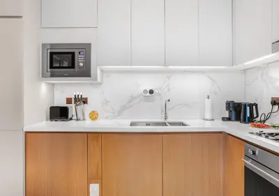 a white kitchen with a sink and a microwave at Ultra-Luxury Burj & Fountain Suite at Address Opera in Dubai