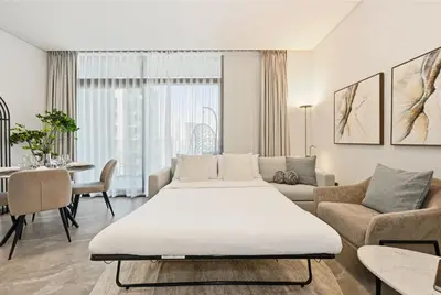 a living room with a large bed and a couch at Spacious & Cozy 2BD Apartment Peninsula One, Dubai in Dubai