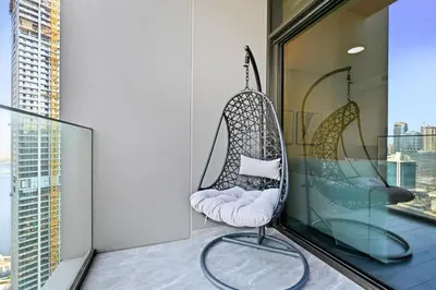 a hanging chair on a balcony with a view at Spacious & Cozy 2BD Apartment Peninsula One, Dubai in Dubai