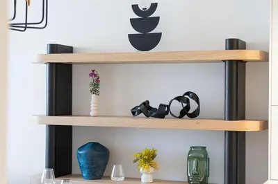 a wooden shelf with glasses and vases on it at New Luxury Canalfront 2 Bedroom Apartment with Burj Views in Dubai